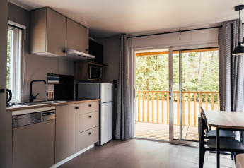 Moderne indendørs lodge køkken med åbne skydedøre til træterrasse, Loggia Wood, Eurocamping Vessem, Holland.