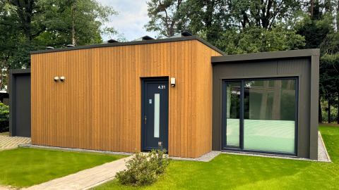 Moderne Forest Lodge bij Holiday Park BreeBronne in Nederland, met houten afwerking en grote ramen in het groen.