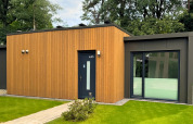 Moderne Forest Lodge im Holiday Park BreeBronne, Niederlande, mit Holzfassade und großen Fenstern im Grünen.