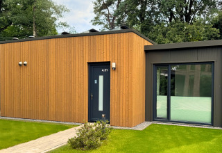 Modern Forest Lodge at Holiday Park BreeBronne in the Netherlands, with wood siding and large windows, set in greenery.