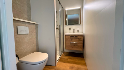 Moderne badkamer met toilet, douche en houten wasmeubel in Forest Lodge, BreeBronne, Nederland.