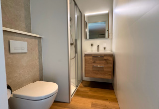 Modernes Badezimmer mit Toilette, Dusche und Holzwaschtisch in der Forest Lodge im BreeBronne Park, Niederlande.