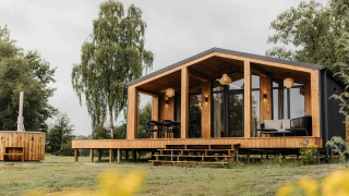 Panorama Lake House Scandi met hottub, moderne houten lodge met terras in een groene omgeving.