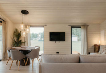 Modernes Wohnzimmer im Panorama Lake House Scandi mit Rundtisch, grauem Sofa und Panoramablick in Wilsumer Berge.