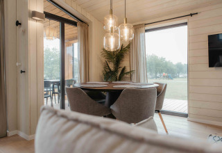 Eethoek in Panorama Lake House Scandi met grote ramen, grijze stoelen en moderne hanglampen.