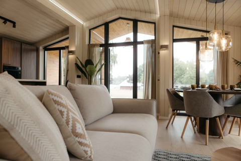 Lichte, moderne woonkamer in Panorama Lake House Scandi bij Wilsumer Berge met grote ramen en eethoek.