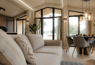 Lichte, moderne woonkamer in Panorama Lake House Scandi bij Wilsumer Berge met grote ramen en eethoek.