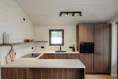 Moderne keuken in Panorama Lake House Scandi met houten kasten, witte wanden en een gezellig interieur.