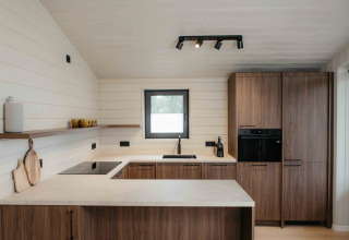 Moderne keuken in Panorama Lake House Scandi met houten kasten, witte wanden en een gezellig interieur.