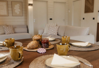 Scandinavische woonkamer in Panorama Lake House met ontbijttafel, brood en koffie in Wilsumer Berge.