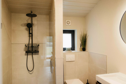 Moderne badkamer met douche, toilet, zwarte kranen en decoratie in Panorama Lake House Scandi bij Wilsumer Berge, Duitsland.