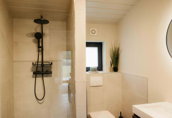 Modernes Bad mit Dusche, WC, schwarzer Armatur und Pflanze im Panorama Lake House Scandi am Wilsumer Berge.