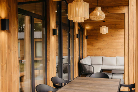 Knus overdekt terras bij Panorama Lake House Scandi met bank, tafel en verlichting in Wilsumer Berge.