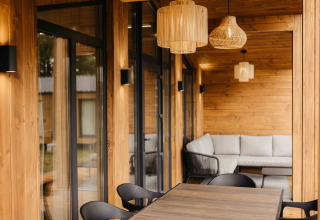 Knus overdekt terras bij Panorama Lake House Scandi met bank, tafel en verlichting in Wilsumer Berge.