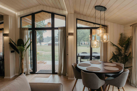 Modern Panorama Lake House Scandi hutinterieur bij Wilsumer Berge met eethoek en grote ramen.