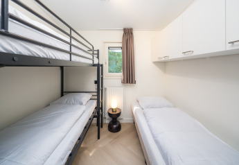 Moderne lodgeværelse på Loevestein Comfort i Veluwepark de Bosgraaf med køjeseng og enkeltseng.