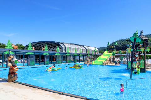 Outdoor swimming pool with kid-friendly slides and animal statues at Camping Nommerlayen, Luxembourg, on a sunny day.