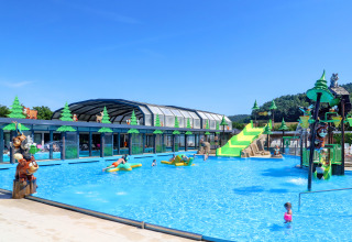 Outdoor swimming pool with kid-friendly slides and animal statues at Camping Nommerlayen, Luxembourg, on a sunny day.