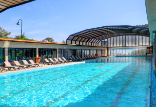 Piscina cubierta y al aire libre con tumbonas en Camping Nommerlayen, parque vacacional en Luxemburgo.