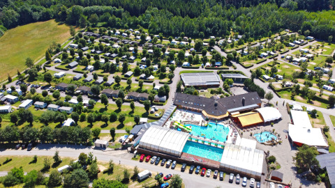 Aerial view of Camping Nommerlayen holiday park in Luxembourg featuring a pool, cabins, and campsites.