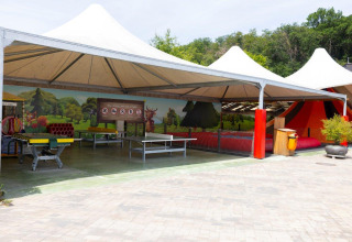 Zona de juegos al aire libre con mesas y mural colorido en Camping Nommerlayen en Luxemburgo, Luxemburgo.