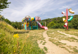 Spielplatz mit bunten Rutschen und Klettergerüsten im Grünen im Ferienpark Camping Nommerlayen, Luxemburg.