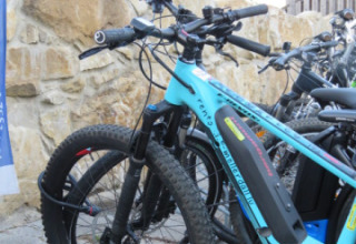 Electric bicycle parked near a stone wall at Camping Nommerlayen, a holiday park in Luxembourg.