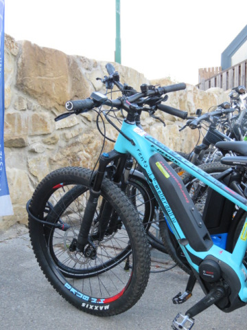 Bicicletta elettrica parcheggiata vicino a un muro di pietra al Camping Nommerlayen in Lussemburgo.