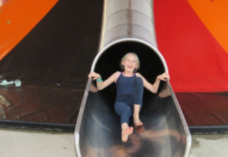 Un bambino si diverte su uno scivolo grande al Camping Nommerlayen, parco vacanze in Lussemburgo.