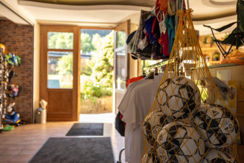 Ingresso di un negozio di campeggio con palloni da calcio in rete e abbigliamento a Nommerlayen, Lussemburgo.