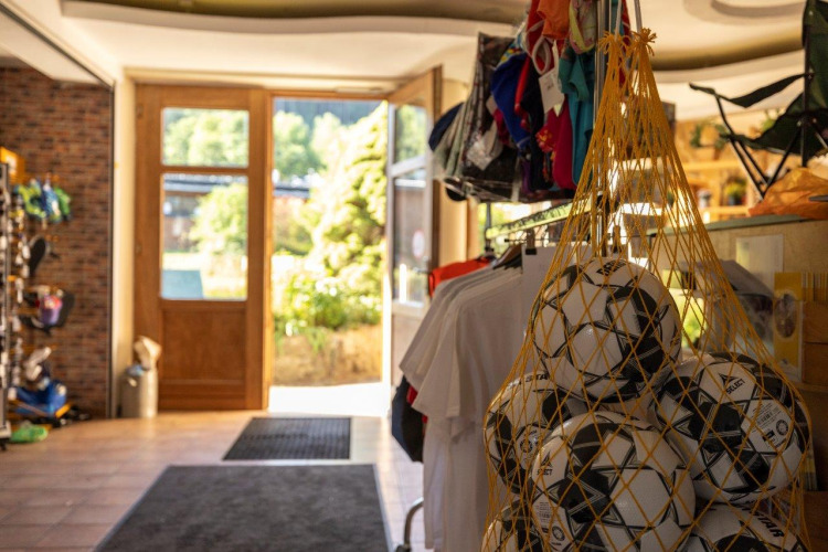 Entrada de una tienda de camping con balones de fútbol en red y ropa en Camping Nommerlayen en Luxemburgo.