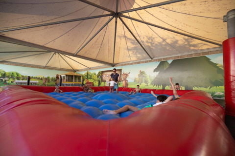 Children play on a large inflatable jumping pillow under a tent at Camping Nommerlayen in Luxembourg.