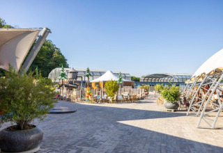 Outdoor seating area at Camping Nommerlayen holiday park in Luxembourg, with pavilions and greenery.