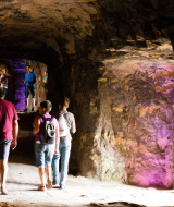 People walking inside a brightly lit cave with illuminated rock walls near Nommern, Luxembourg, Europe.