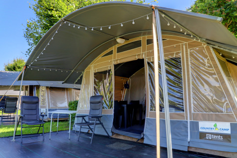 Tenda lodge confortevole con sedie e luci, perfetta per un'esperienza di glamping rilassante nella natura.