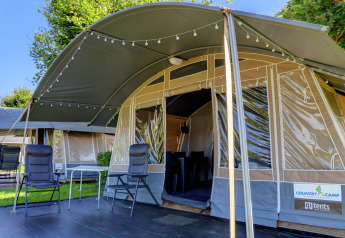 Comfortabele lodgetent met zitjes en sfeerverlichting, ideaal voor een gezellige glampingvakantie in het groen.