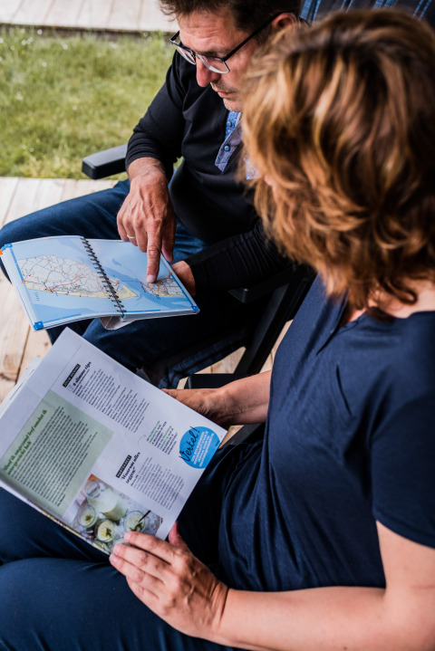 Due persone alla Nommerlayen Lodge in Lussemburgo guardano insieme una mappa e una brochure.