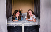 Deux jeunes femmes se détendent et sourient sur un lit double dans une chambre confortable d'un lodge.