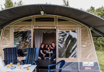 Gezin beleeft plezier samen in een moderne tentlodge, met comfortabele stoelen en sap op tafel.