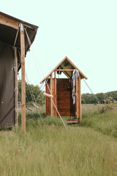 Ducha exterior de madera en un parque vacacional en Friesland, Países Bajos, rodeada de naturaleza.