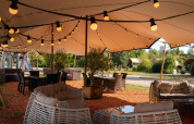 Sfeervolle loungeplek met rieten meubels, verlichting en overkapping bij Holiday Resort 't Schuttenbelt.