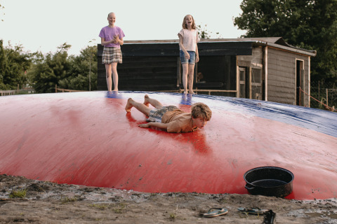 Children play on a large inflatable air pillow at Feather Down De Appelsche holiday park, Friesland, Netherlands.