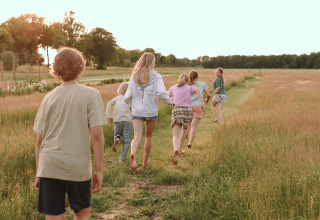 Niños corriendo en un prado en Feather Down De Appelsche, parque vacacional en Friesland, Países Bajos.