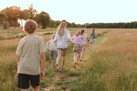 Bambini che corrono in un prato al parco vacanze Feather Down De Appelsche in Frisia, Paesi Bassi.