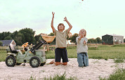 Twee kinderen spelen met een speelgoedtractor in het zand bij Feather Down De Appelsche, Friesland.