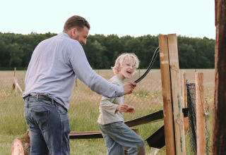 Padre ayuda a niño sonriente a ducharse al aire libre en Feather Down De Appelsche, Friesland, Países Bajos.