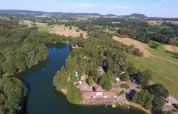 Vista aerea del parco vacanze Domaine des Messires con lago, boschi e campi in Grand Est, Francia.