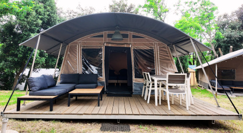 Moderne glamping tent met overdekt terras en zithoek bij Domaine des Messires in Grand Est, Frankrijk.
