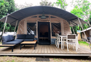 Modern glamping tent with shaded terrace, sofa, and dining set at Domaine des Messires in Grand Est, France.