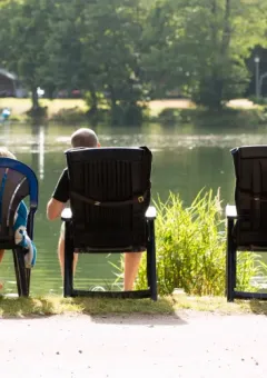 Two people relax by the lake at Domaine des Messires holiday park in Grand Est, France, enjoying nature.